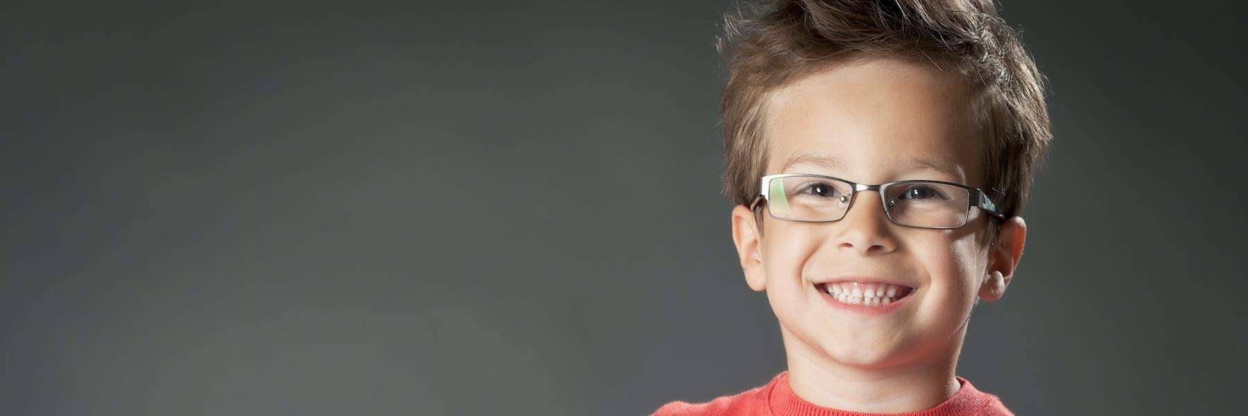 A smiling young boy wearing glasses and a red sweater.